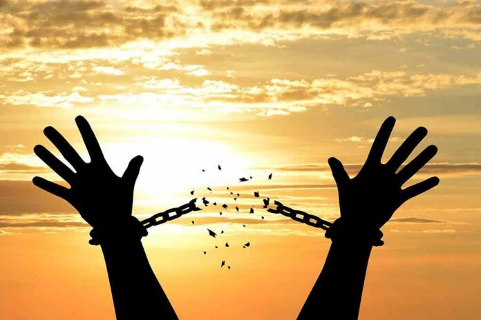 Silhouette hands breaking chains at sunset
