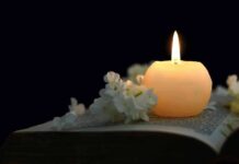 Candle on an open book with white flowers
