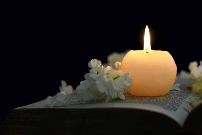 shutterstock_1031056267 Candle on an open book with white flowers