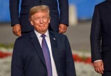 Career Threat Over Trump Jobs Sparks Uproar smiling man in a navy suit at an outdoor event