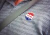 Outrage Erupts Over Palm Beach Endorsement I voted sticker on a gray shirt under a seat belt