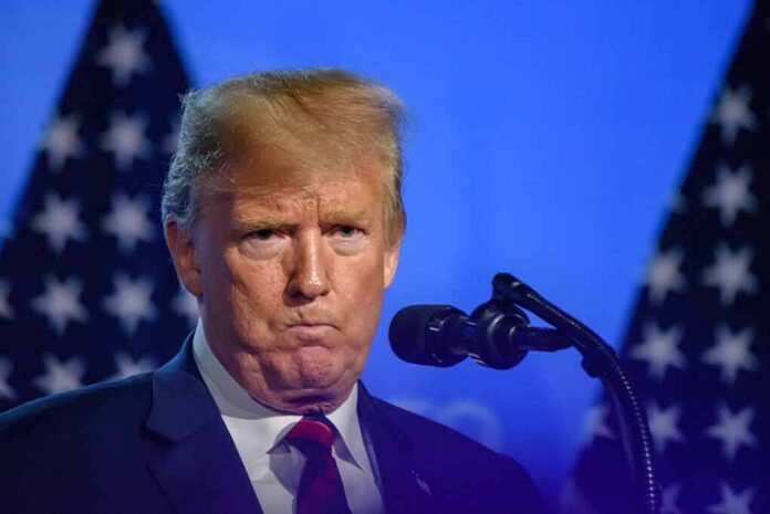 shutterstock_1358576072 Donald Trump at a podium with U.S. flags in the background