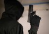 Hooded person holding a handgun