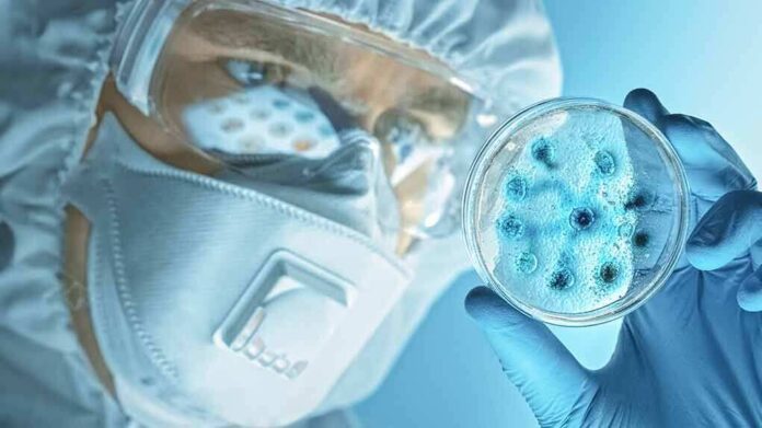 shutterstock_1672672939 Scientist in protective gear examining a petri dish