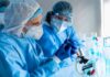 CDC Drops Bomb On Infertility Rumors Scientists in protective gear working with a syringe in a laboratory