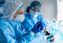 CDC Drops Bomb On Infertility Rumors Scientists in protective gear working with a syringe in a laboratory