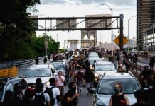 Jonathan Cyprien and Andreas Hestler among a crowd walking between cars on a busy bridge