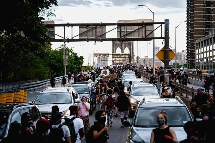 Jonathan Cyprien and Andreas Hestler among a crowd walking between cars on a busy bridge