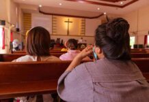 people seated in church pews facing a cross