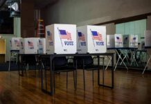 Late Ruling Jolts New Hampshire Ballots Voting booths with American flags in an empty polling place