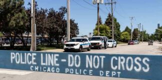 Police line barrier blocking a street with patrol vehicles behind