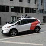 Cost Bomb Threatens Robotaxi Rollout Autonomous test car with roof sensors on a city street