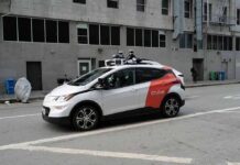 Cost Bomb Threatens Robotaxi Rollout Autonomous test car with roof sensors on a city street