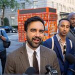 Mayor Demands ICE Halt After Car Shooting Zohran Mamdani speaking to reporters on a city sidewalk