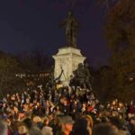 Peace Vigil SWARMED – Cops Rush In Crowd holding candles around a large statue at night