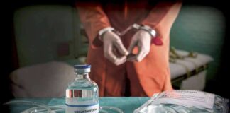 Medical vials and IV lines on a table with a handcuffed person in the background