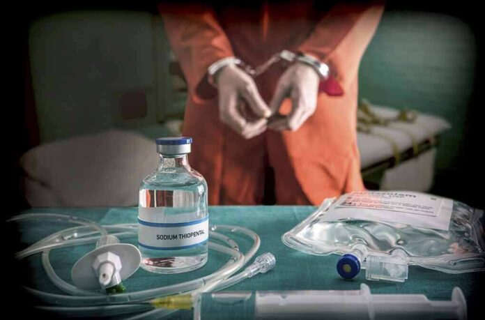 shutterstock_765745765 Medical vials and IV lines on a table with a handcuffed person in the background